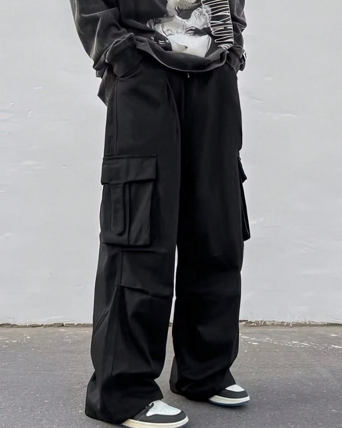 Person wearing black cargo pants and a black graphic t-shirt with sneakers.