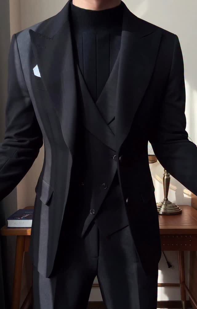 Man wearing a black blazer, waistcoat, and turtleneck sweater for a refined look.