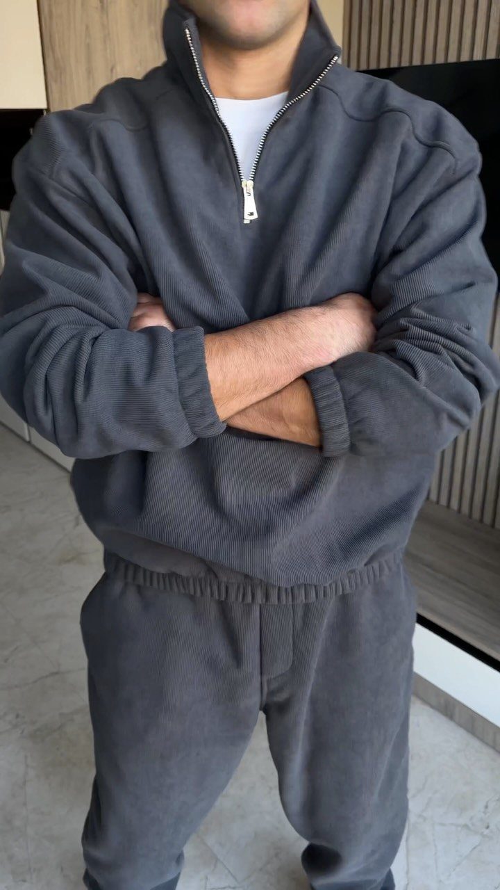 Man wearing a charcoal grey ribbed quarter-zip pullover and matching ribbed joggers.