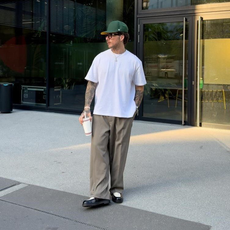 Man wearing a basic white tee, khaki trousers, and a green baseball cap.