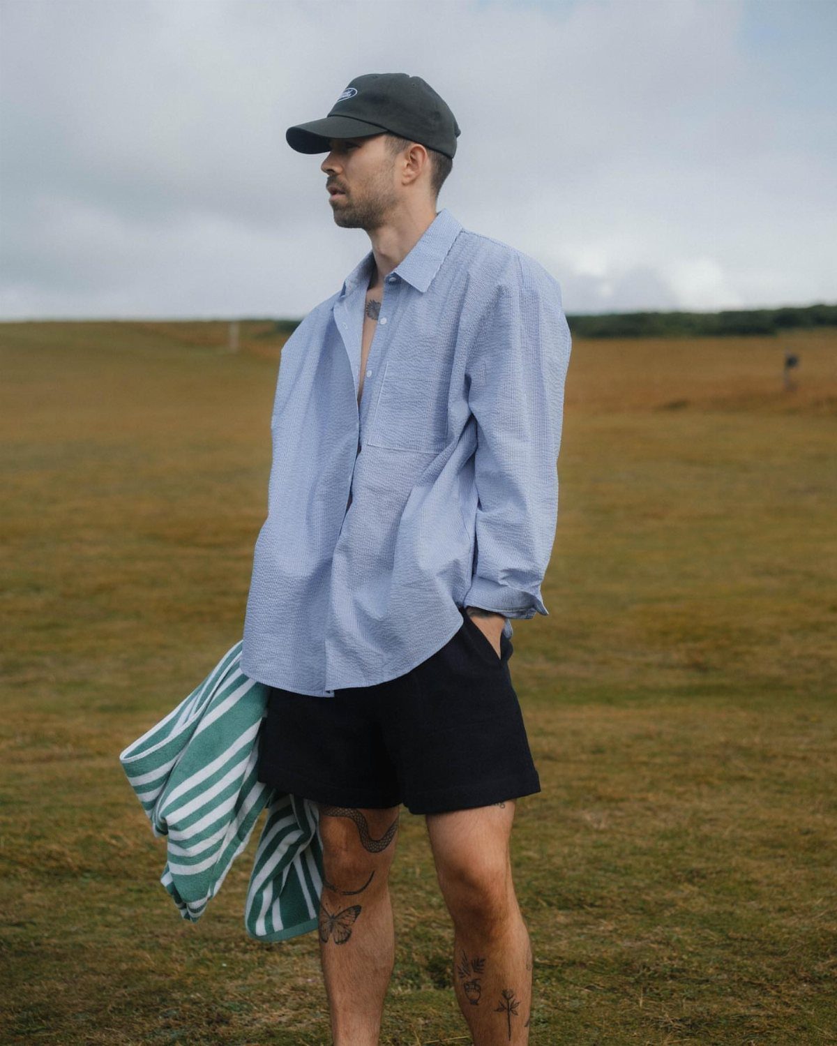 Man in light blue shirt and navy shorts standing in a grassy field