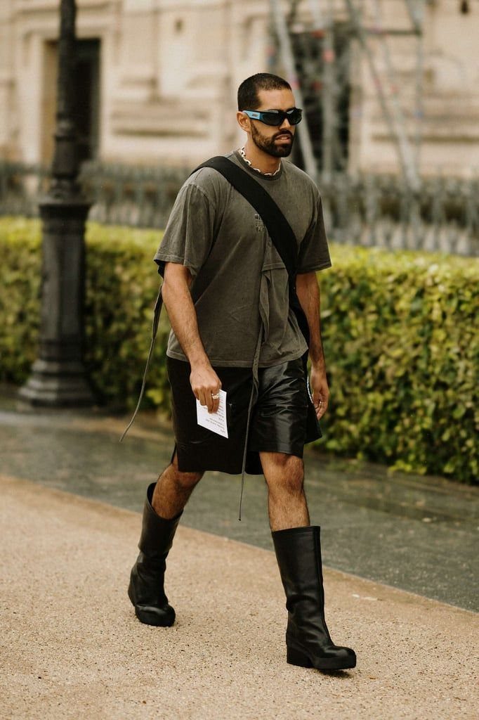 Man wearing a grey t-shirt, black leather bike shorts, and tall black boots.