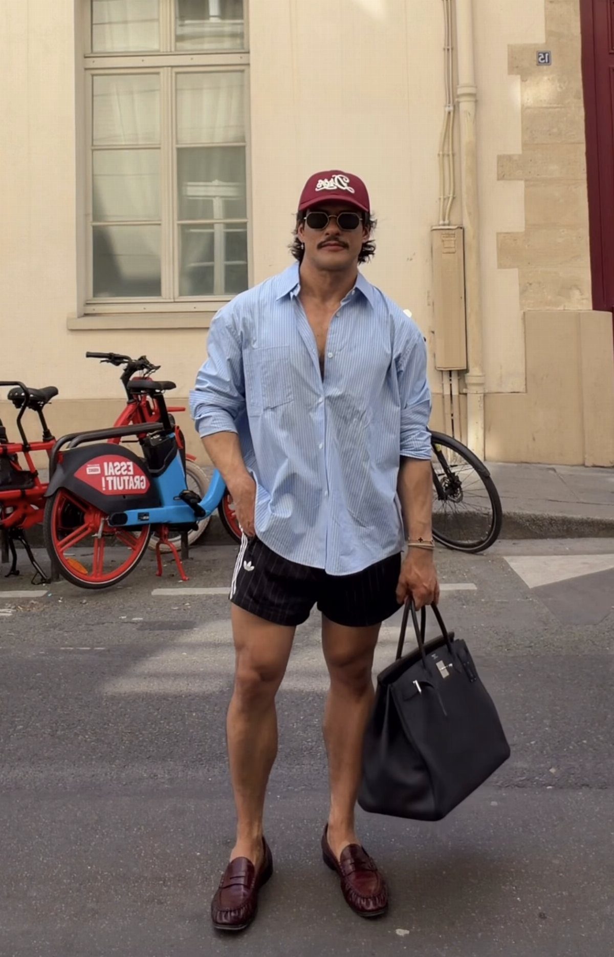 Man wearing a light blue button-down shirt and black biker shorts on a street