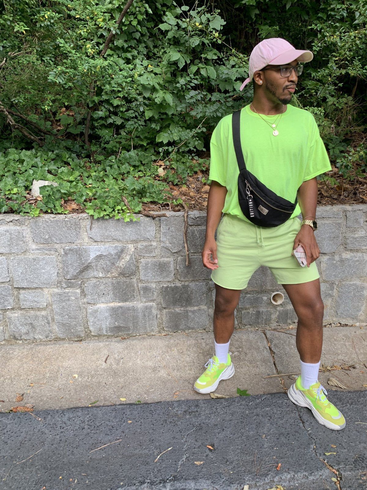 Man wearing neon lime green biker shorts and matching t-shirt with pink cap.