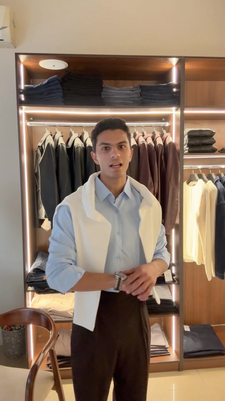 Man wearing a light blue shirt and brown pants in a clothing store