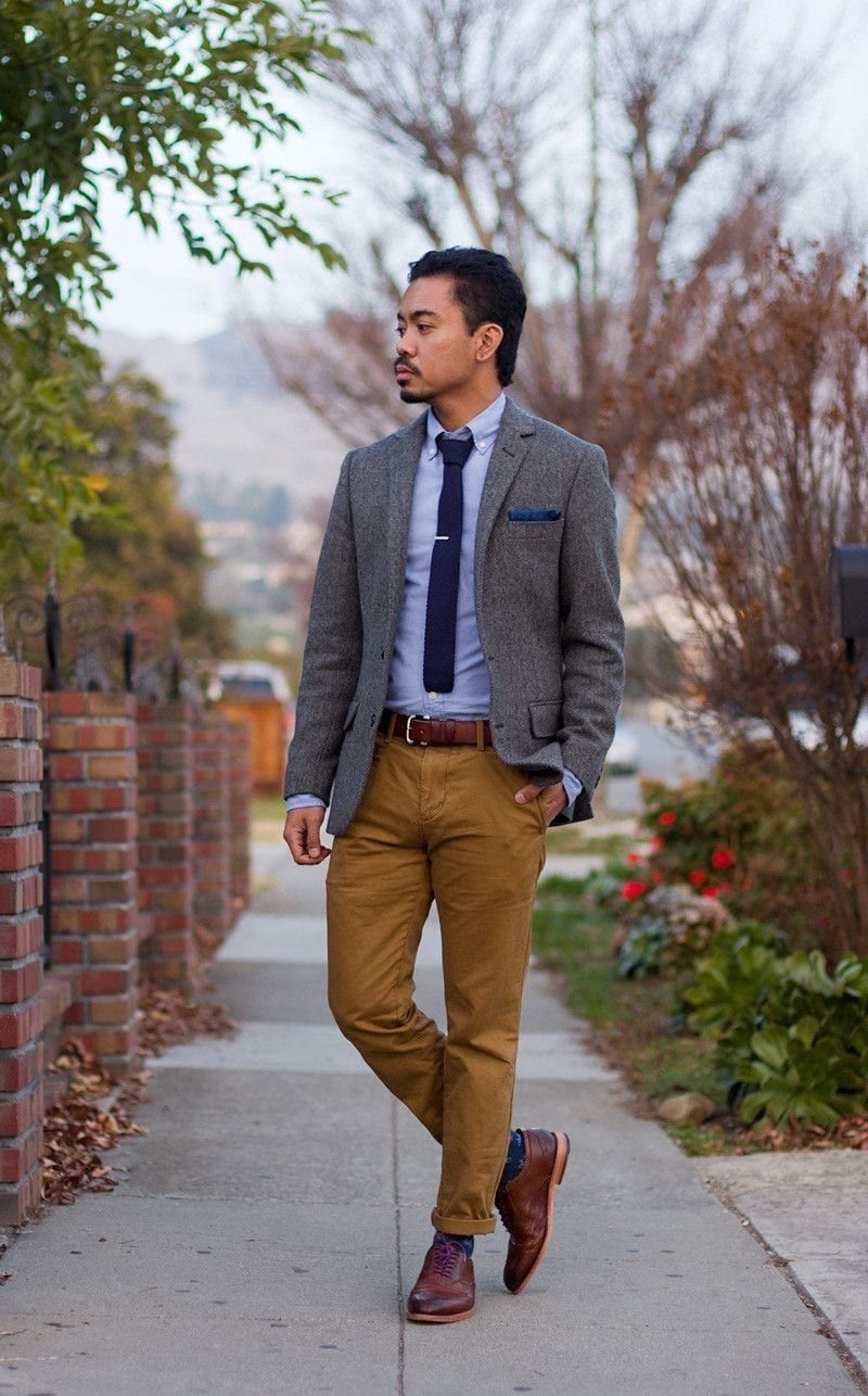 Man wearing grey blazer, blue shirt, and brown pants with brown leather shoes.