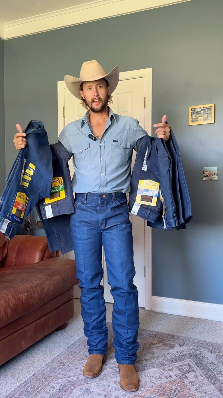 Man in cowboy hat and bootcut jeans holding multiple pairs of denim pants.