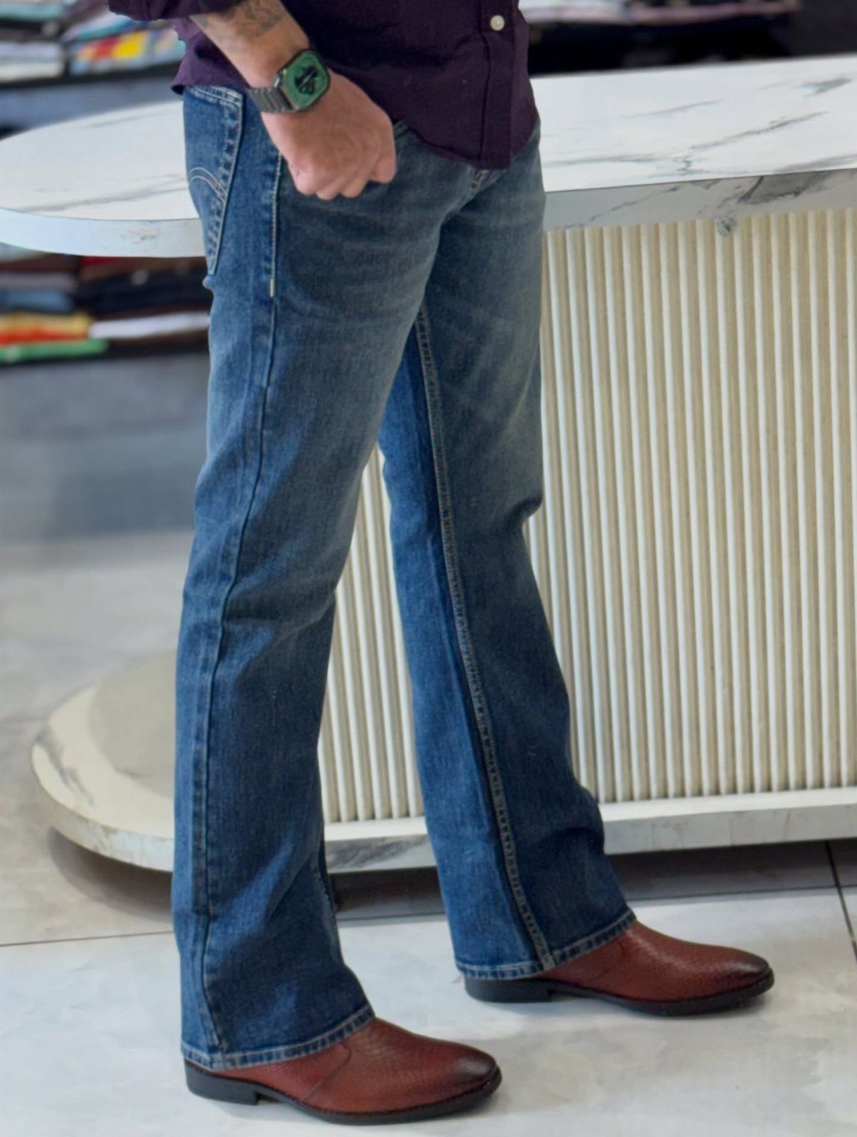 Blue bootcut jeans paired with a purple shirt and brown leather shoes.