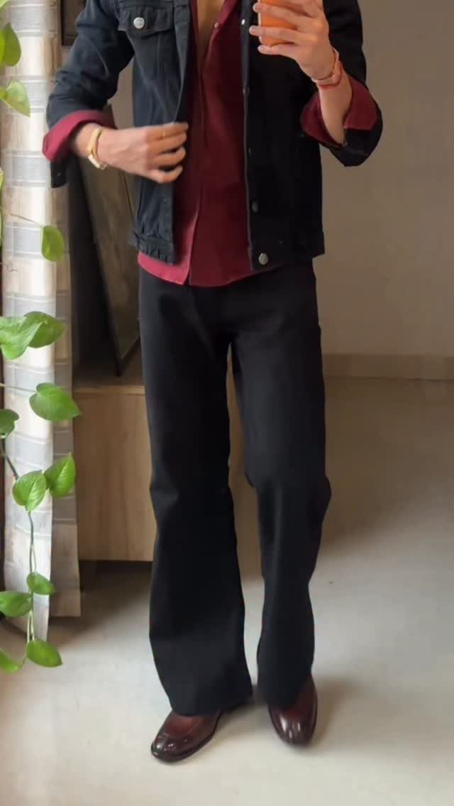 Person wearing a dark denim jacket and black bootcut jeans with brown shoes.