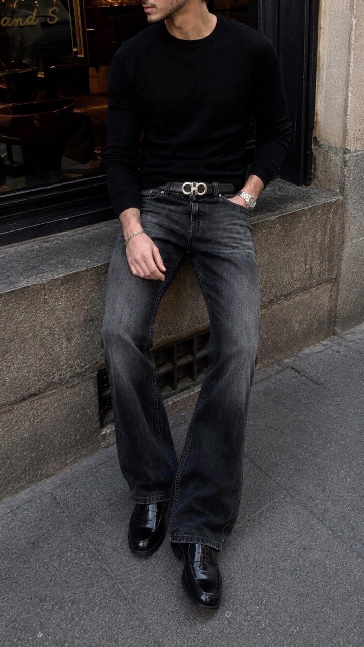 Man in black shirt and dark grey slim bootcut jeans with black shoes.