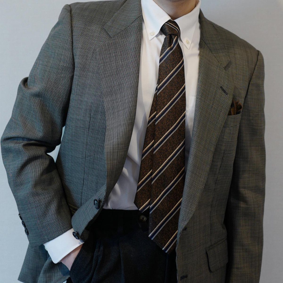 Brown and grey striped tie paired with a grey textured blazer and white shirt.