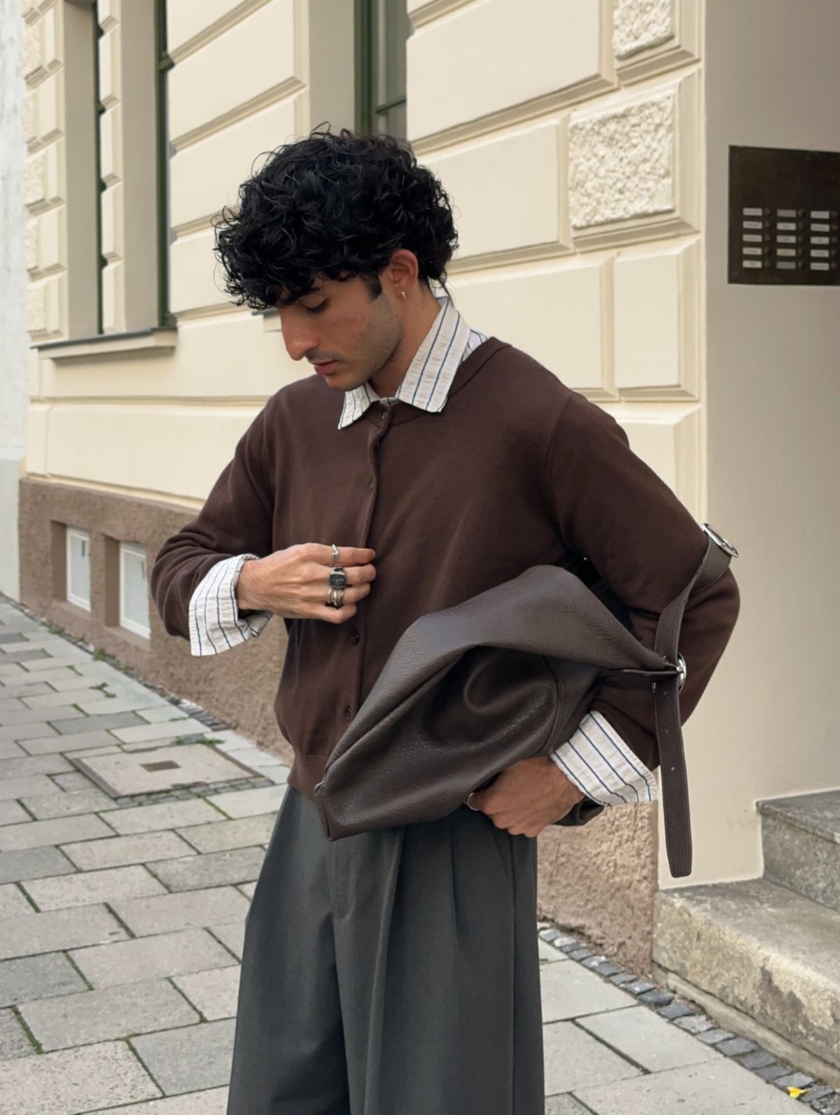 Man wearing a brown polo shirt and grey trousers on a city street