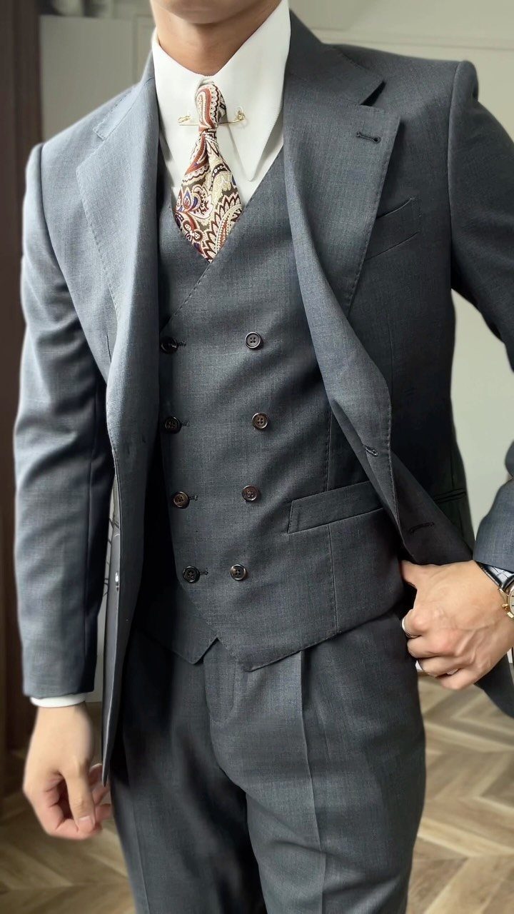 Man in a light grey three-piece suit with a brown patterned tie.