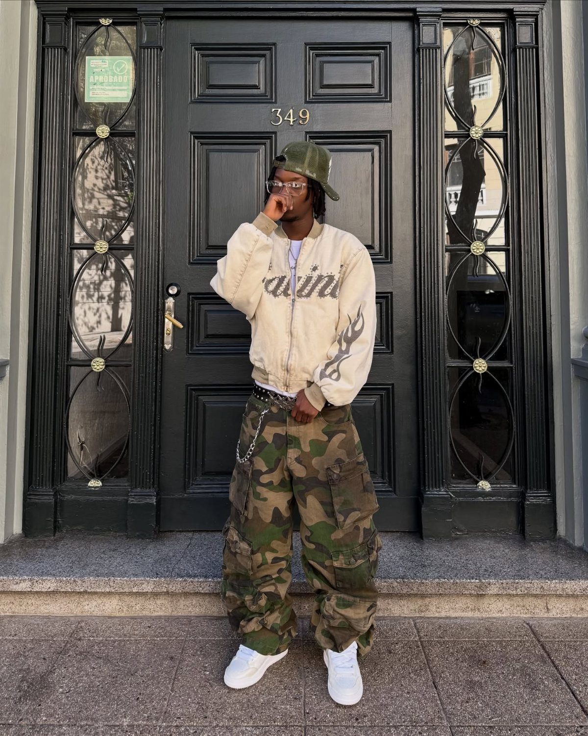 Person wearing a beige bomber jacket, camo cargo pants, and white sneakers.