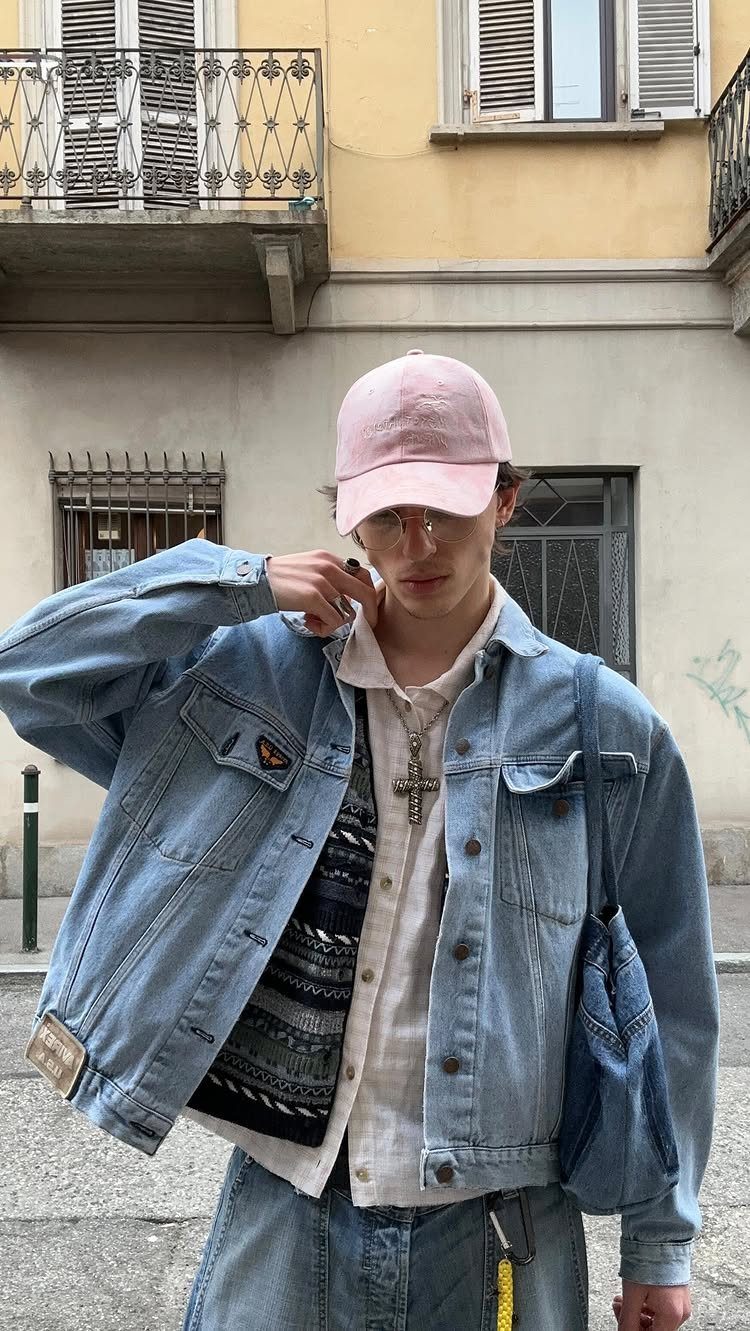 Man wearing a denim jacket over a patterned cardigan and white shirt with jeans.