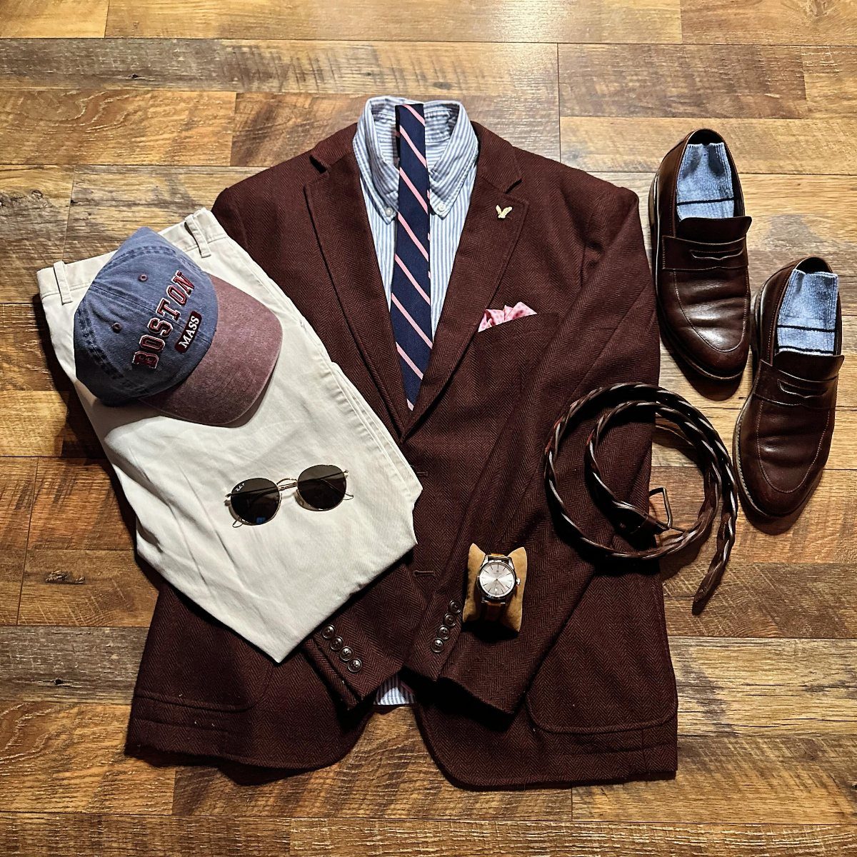 Men's outfit flat lay featuring a burgundy blazer, beige pants, watch, belt, and hat.