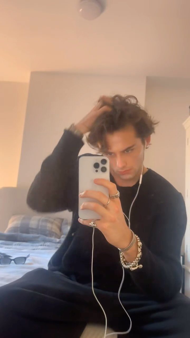 Young man in black outfit wearing silver rings and a chunky chain bracelet.