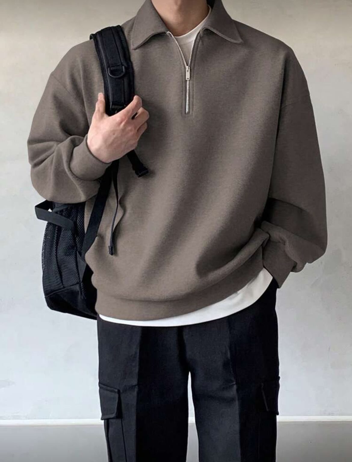 Man wearing a brown quarter-zip sweater, white undershirt, and black cargo pants.