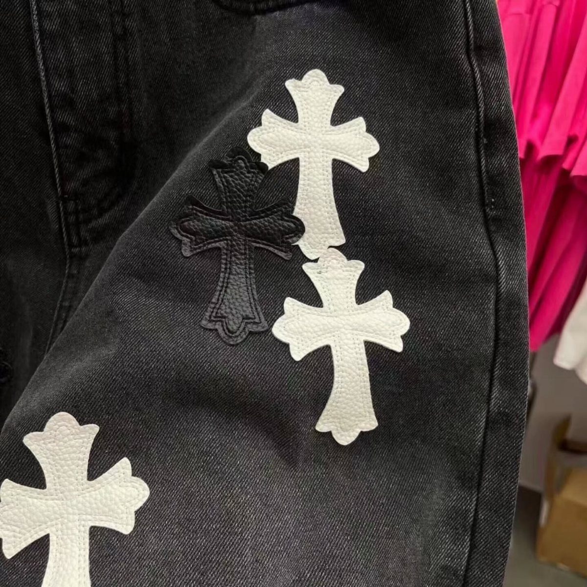 Black denim shorts featuring white and black gothic cross patches on the fabric.