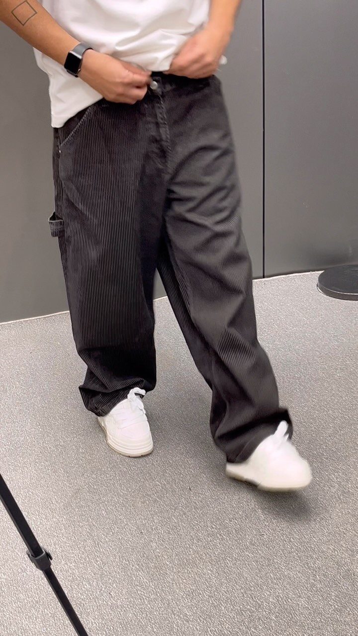 Person wearing wide-leg black corduroy pants, white t-shirt, and white sneakers.