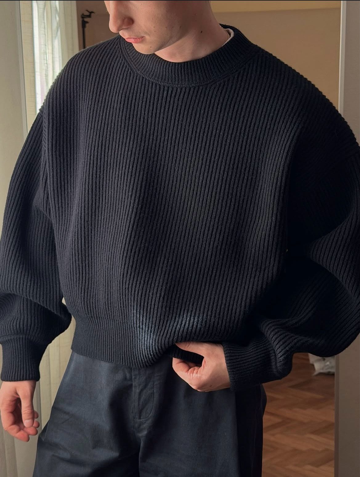 Man wearing a black ribbed cropped crewneck sweater paired with black trousers.