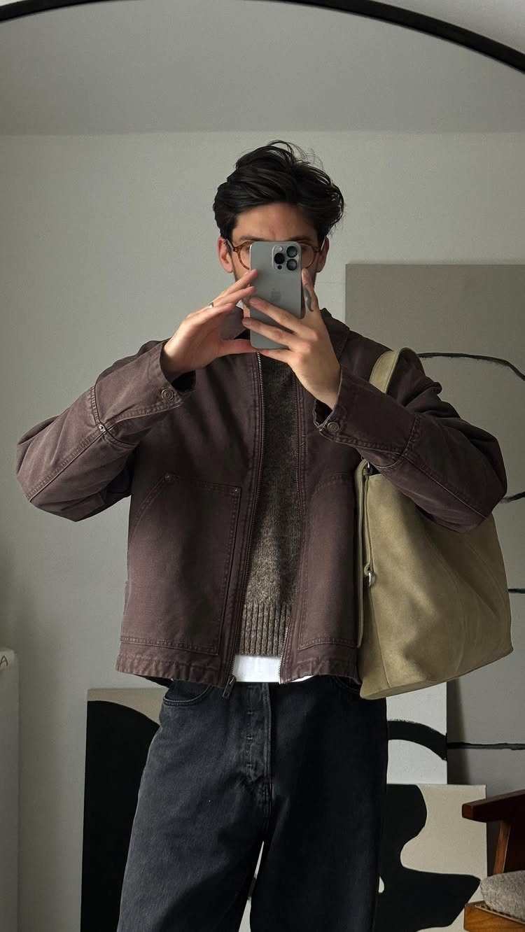 Person in brown jacket and grey sweater holding a light olive tote bag.