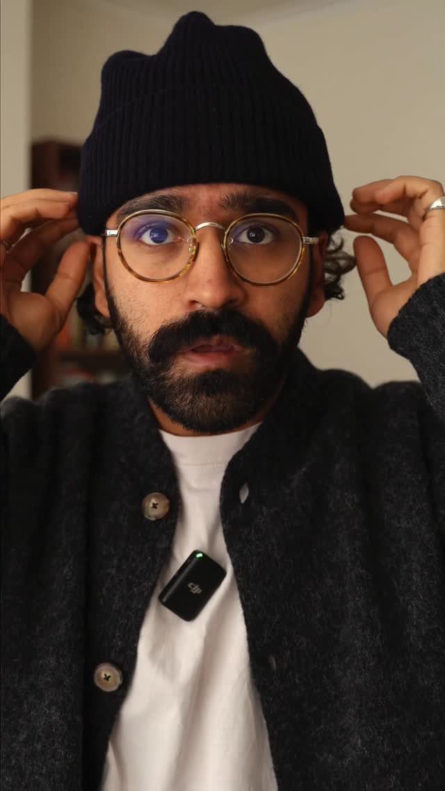 Man wearing a dark gray cardigan over a white t-shirt and black beanie.