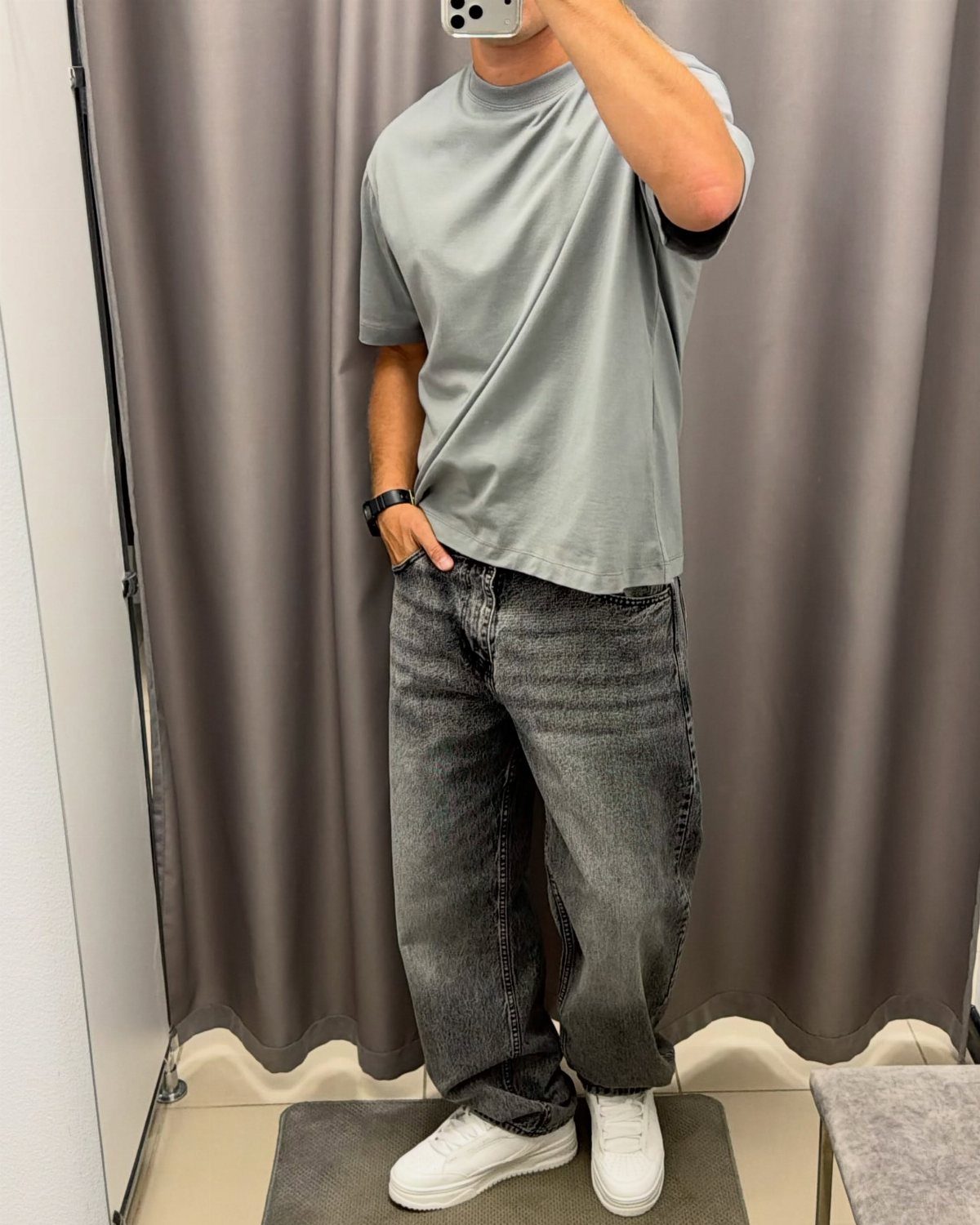 Person wearing a light gray t-shirt, dark gray jeans, and white sneakers.