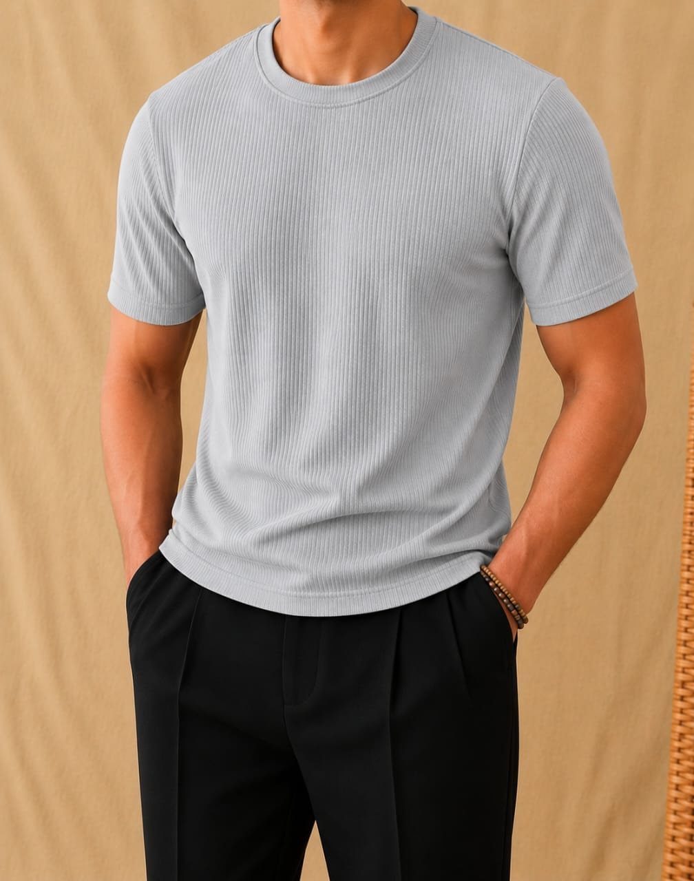 Man wearing a light gray ribbed t-shirt and black pleated trousers.