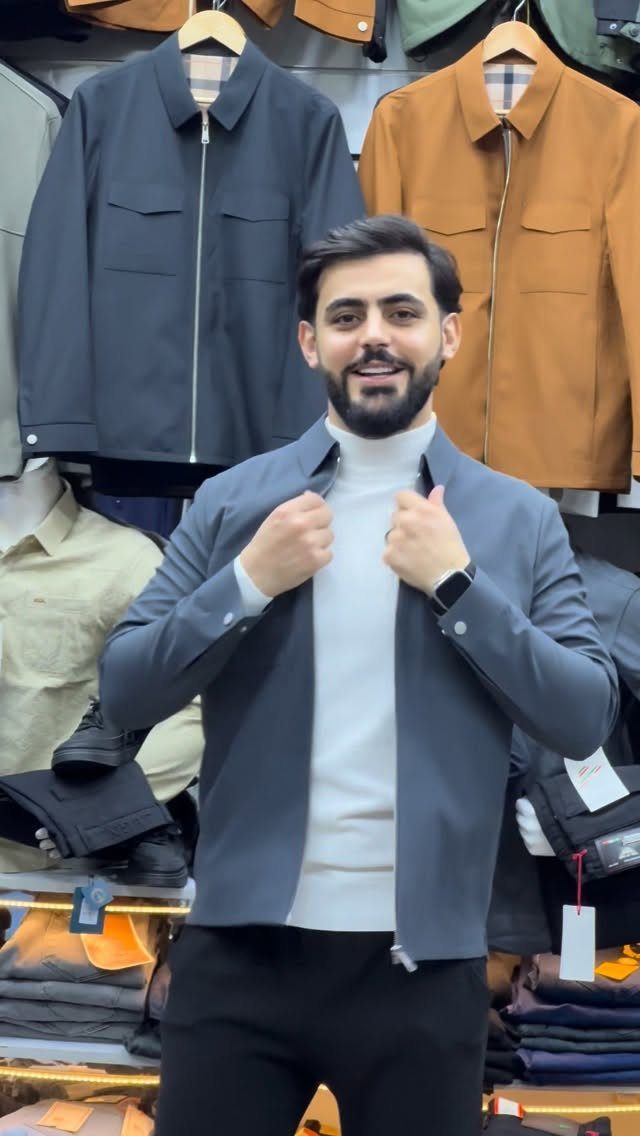 Man wearing a gray zip-up shirt over a white turtleneck in a clothing store