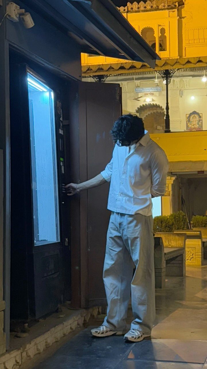 Man in white shirt and grey trousers using a vending machine at night