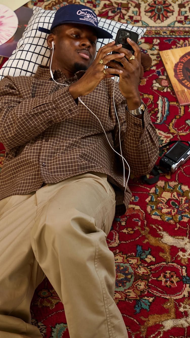 Man in brown checkered shirt and khaki pants lying on a red rug.
