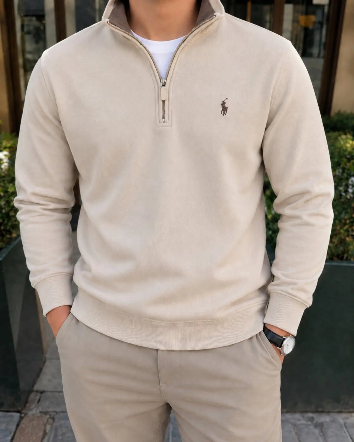 Person wearing a beige quarter-zip sweatshirt and matching khaki pants standing outdoors.
