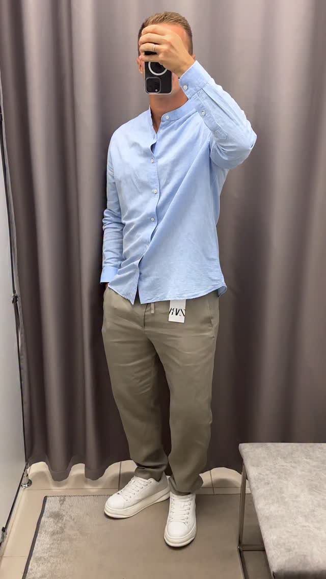 Man wearing a light blue shirt with khaki pants and white sneakers.