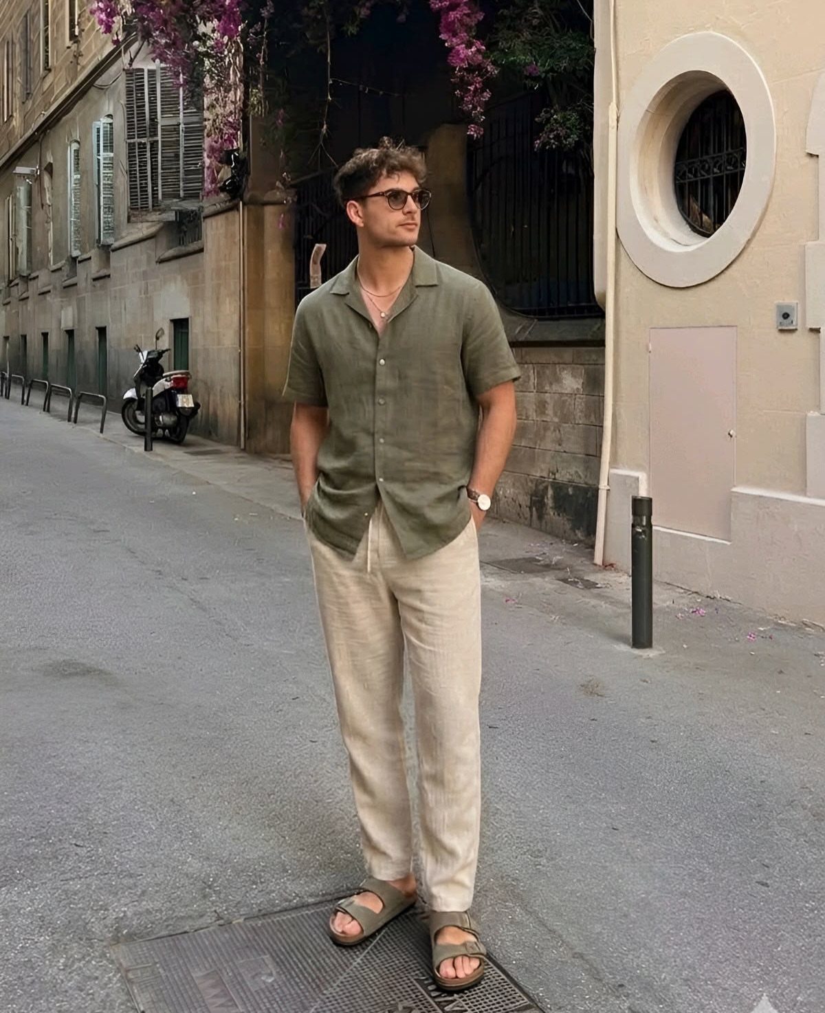 Man wearing olive green short-sleeve shirt and beige linen pants on a city street