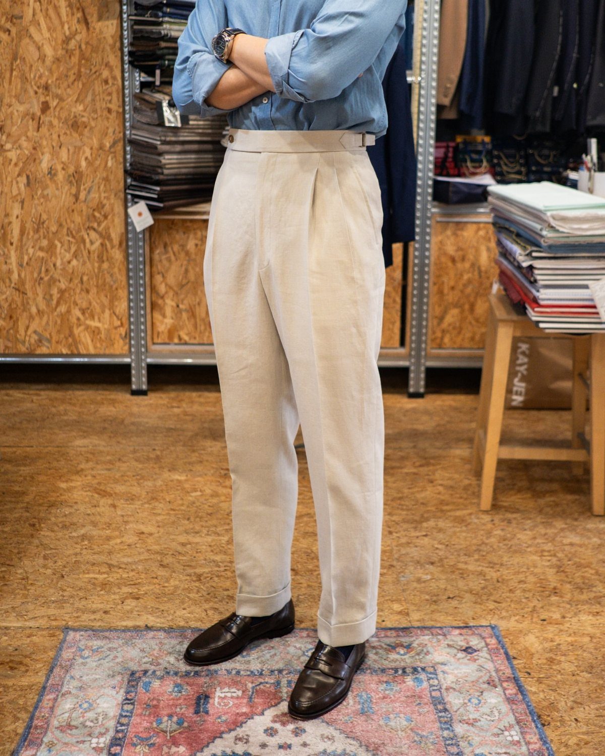 Man wearing off-white pleated linen trousers and a light blue button-down shirt.