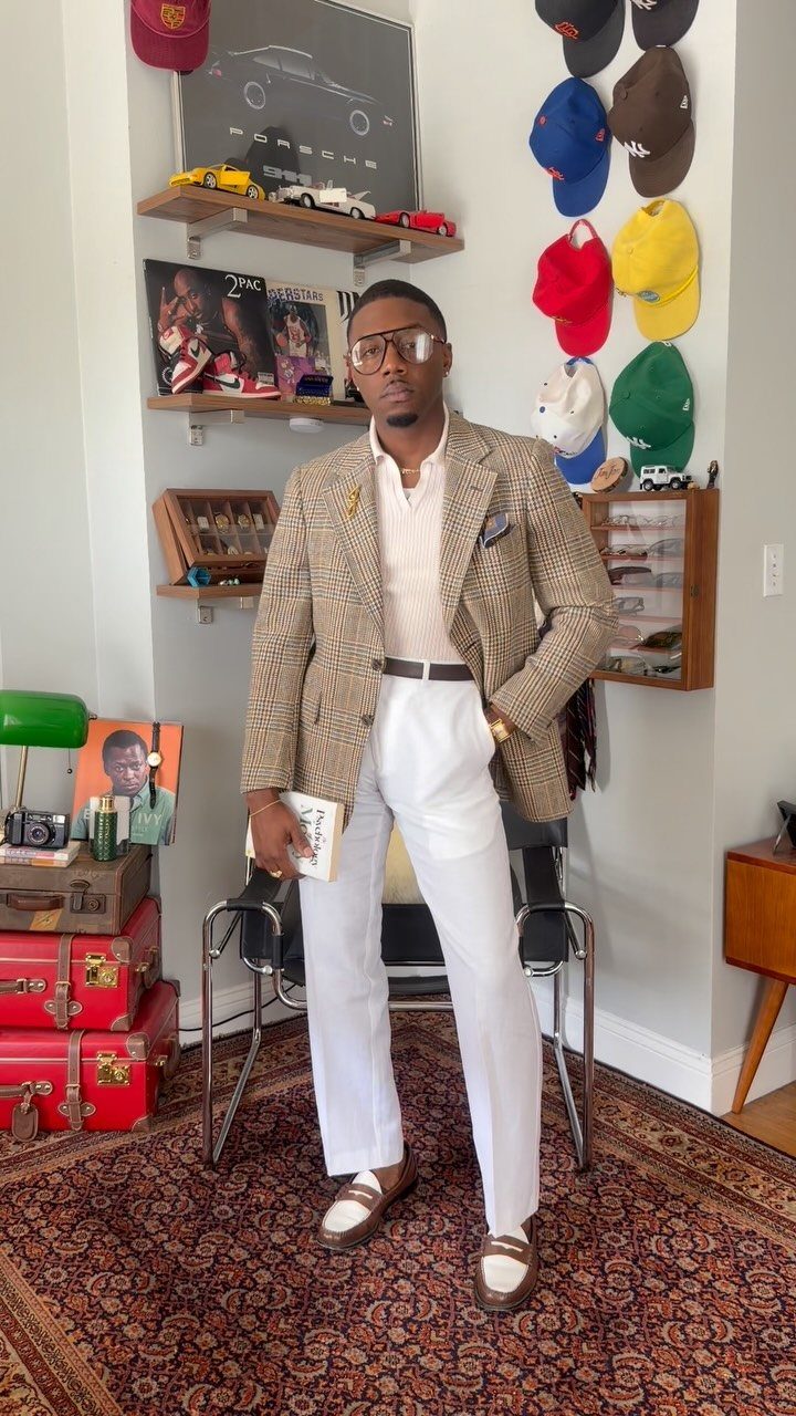 Man wearing a cream polo tucked into white linen pants with a tan blazer.