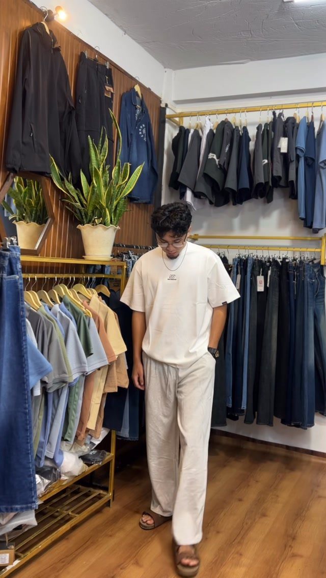 Man wearing a white t-shirt and beige linen pants in a clothing store