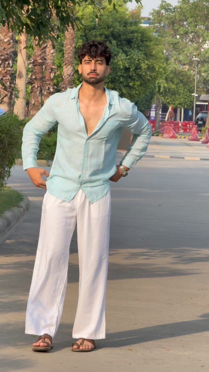 Man wearing a light blue shirt and wide-leg white linen pants outdoors.