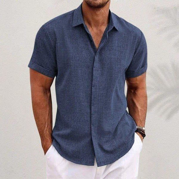 Man wearing a blue short-sleeve linen button-down shirt and white trousers