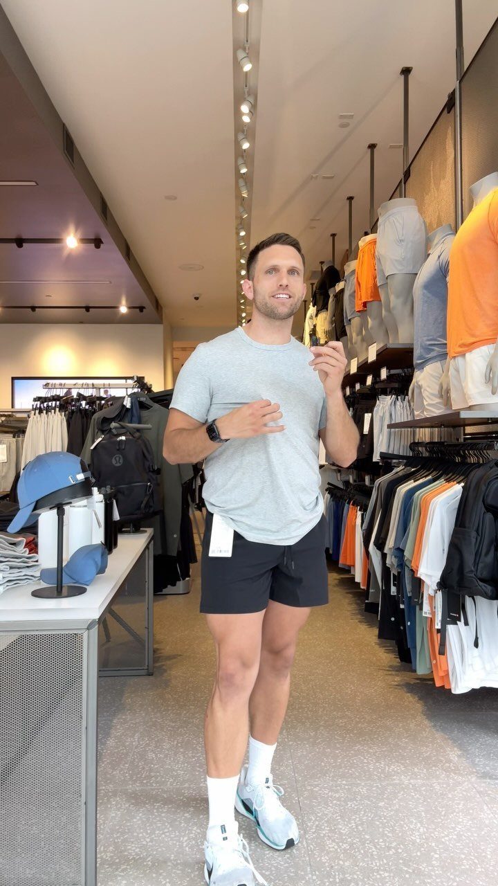 Man wearing a grey t-shirt and black athletic shorts in a clothing store