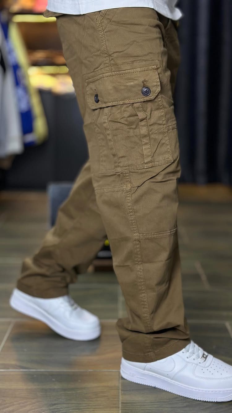 Brown cargo pants with side pockets paired with white sneakers on tiled floor