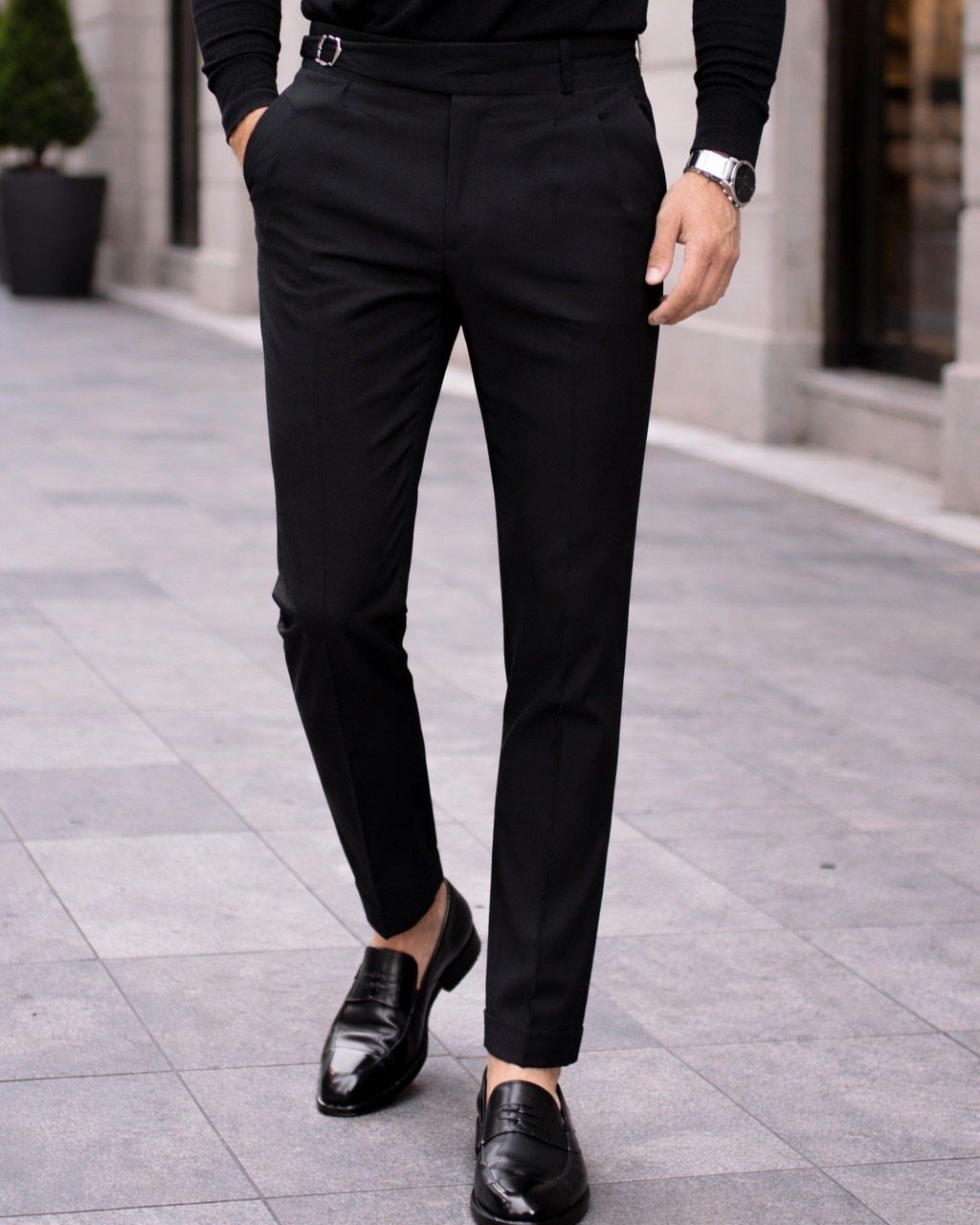 Man wearing slim-fit black tailored trousers and black leather loafers on a sidewalk