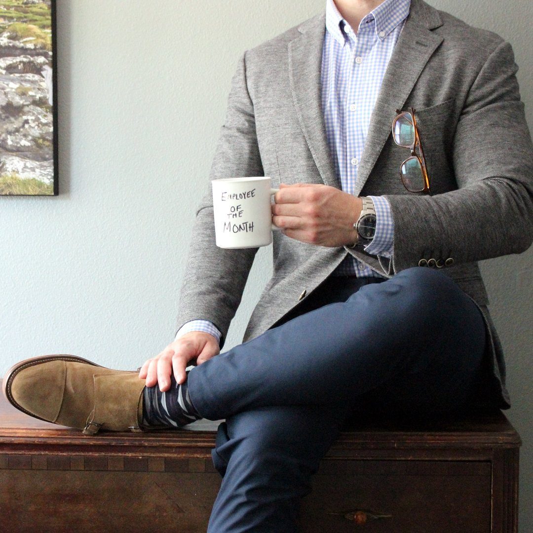 Man in grey blazer and navy trousers holding Employee of the Month mug