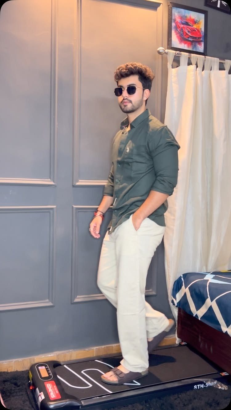 Man in olive green shirt and off-white trousers standing on a treadmill.
