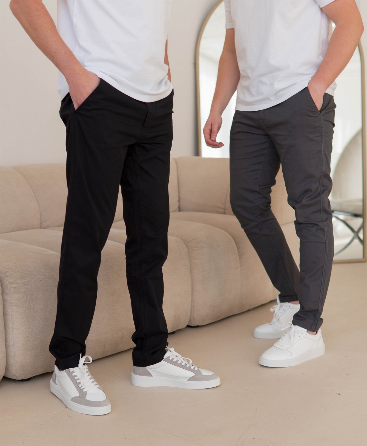 Two men wearing slim-fit black and grey chinos with white sneakers.