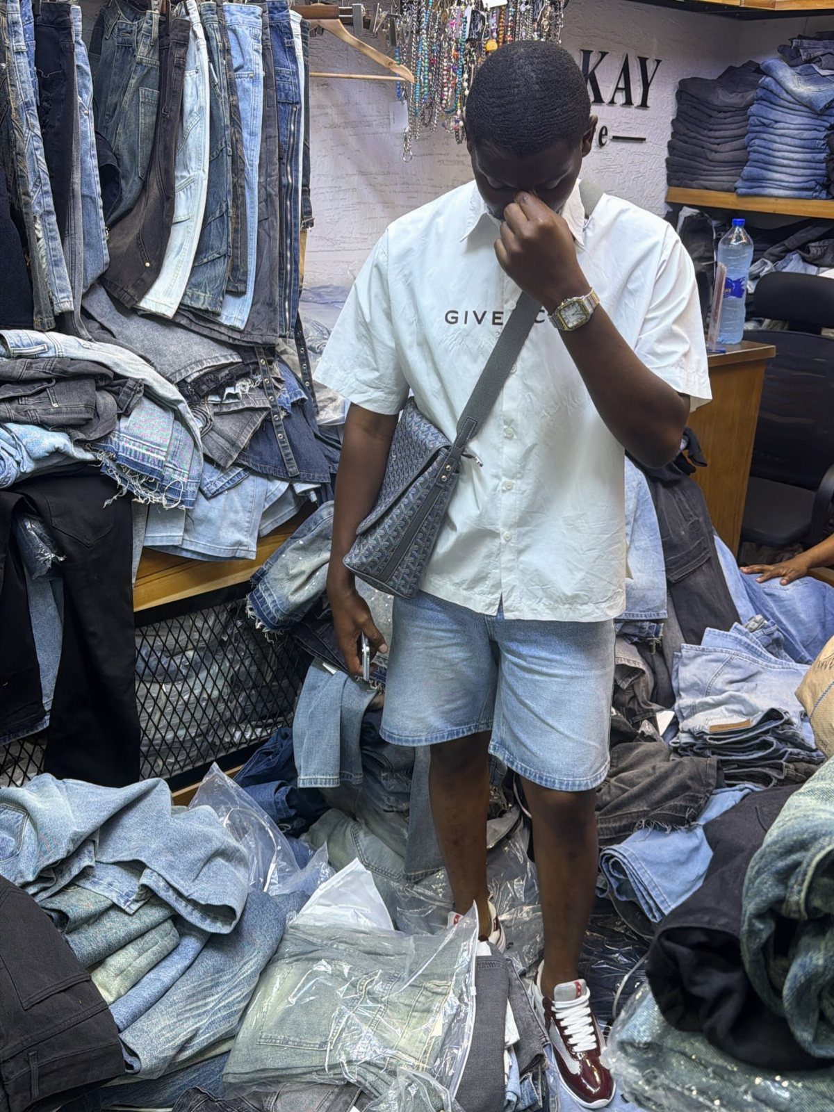 Man wearing light blue denim shorts and white shirt in a clothing store