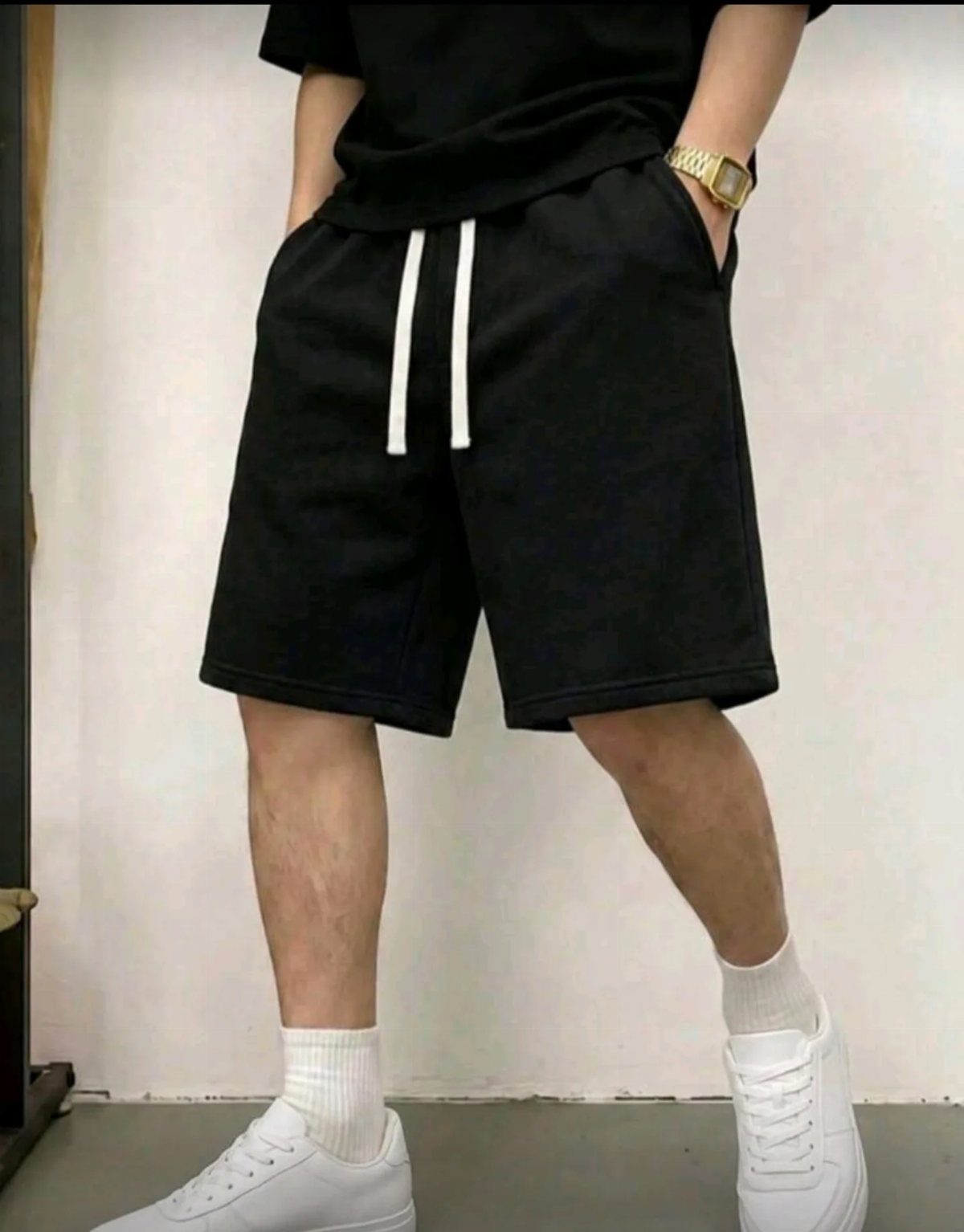 Man wearing black casual drawstring shorts with white sneakers and white socks.