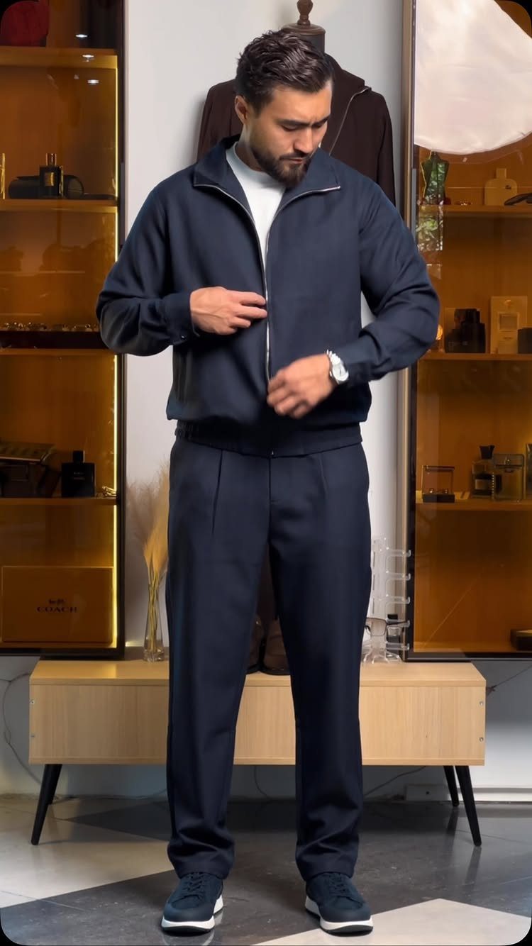 Man wearing a navy blue zip-up jacket and matching navy blue trousers and sneakers.