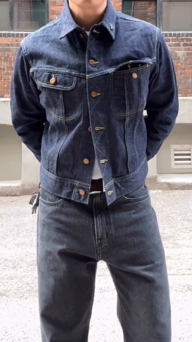 Person wearing a dark navy denim jacket and matching navy denim pants outdoors.